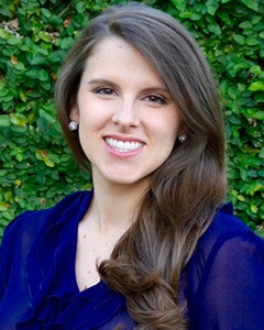 A portrait of Courtney P. Uselton taken in front of a vine-covered wall.